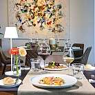 Tavolo apparecchiato con piatti gourmet e decorazioni floreali.
