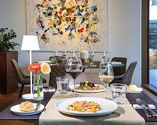 Tavolo apparecchiato con piatti e bicchieri in un ristorante moderno.