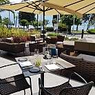 Area esterna di un ristorante con tavoli e divani, vista sul mare.