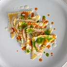 Ravioli decorati con salse su un piatto elegante.
