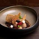 Dessert raffinato con mousse, frutti di bosco e decorazioni croccanti.