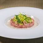 Piatto di tartare di carne con insalata e schiuma decorativa.