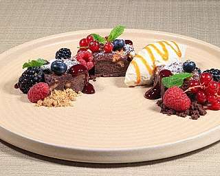 Piatto di dessert al cioccolato con frutti di bosco e gelato.