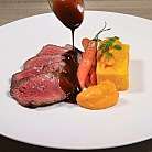 Fette di carne con salsa, carote e purè di zucca.