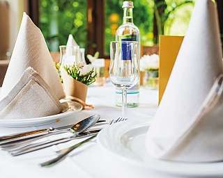 Tavolo apparecchiato con piatti gourmet e decorazioni floreali.