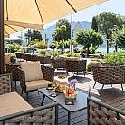 Area esterna di un ristorante con sedie e tavoli, vista sul lago.